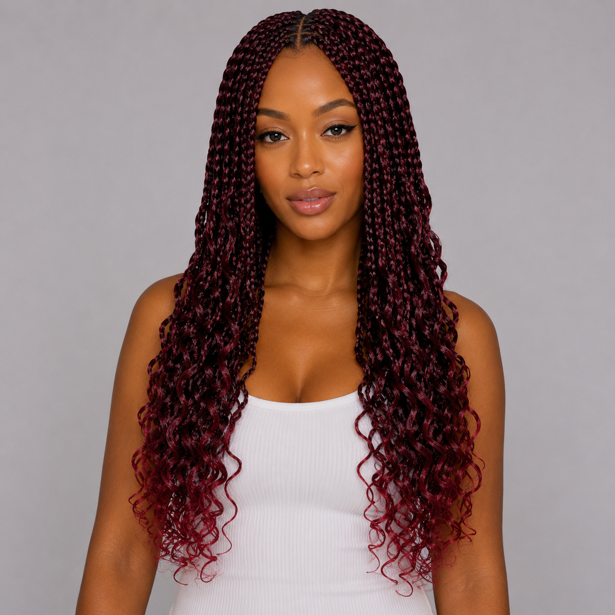 Woman with long, curly burgundy hair against a gray background