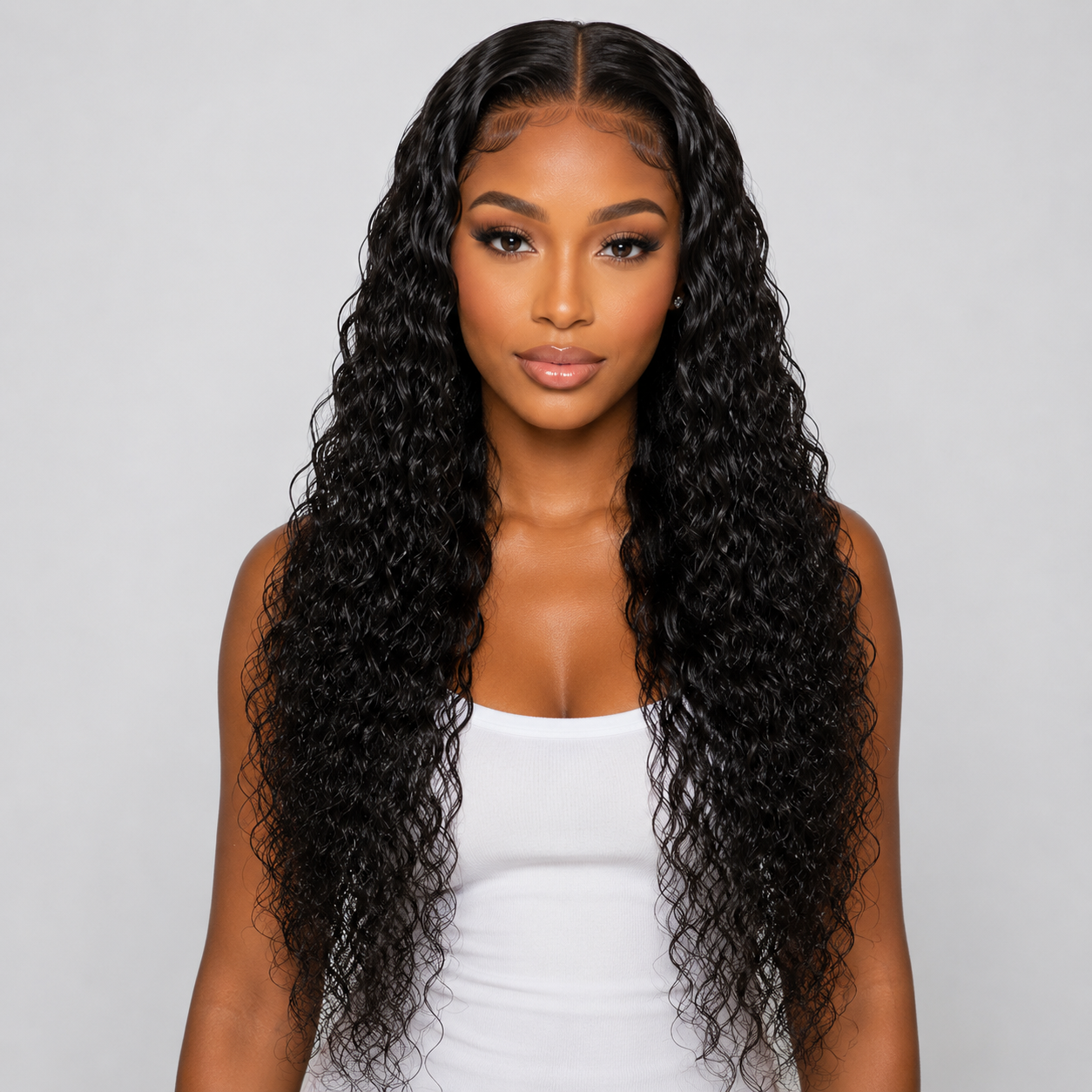 Woman with long, wavy black hair wearing a white top against a gray background